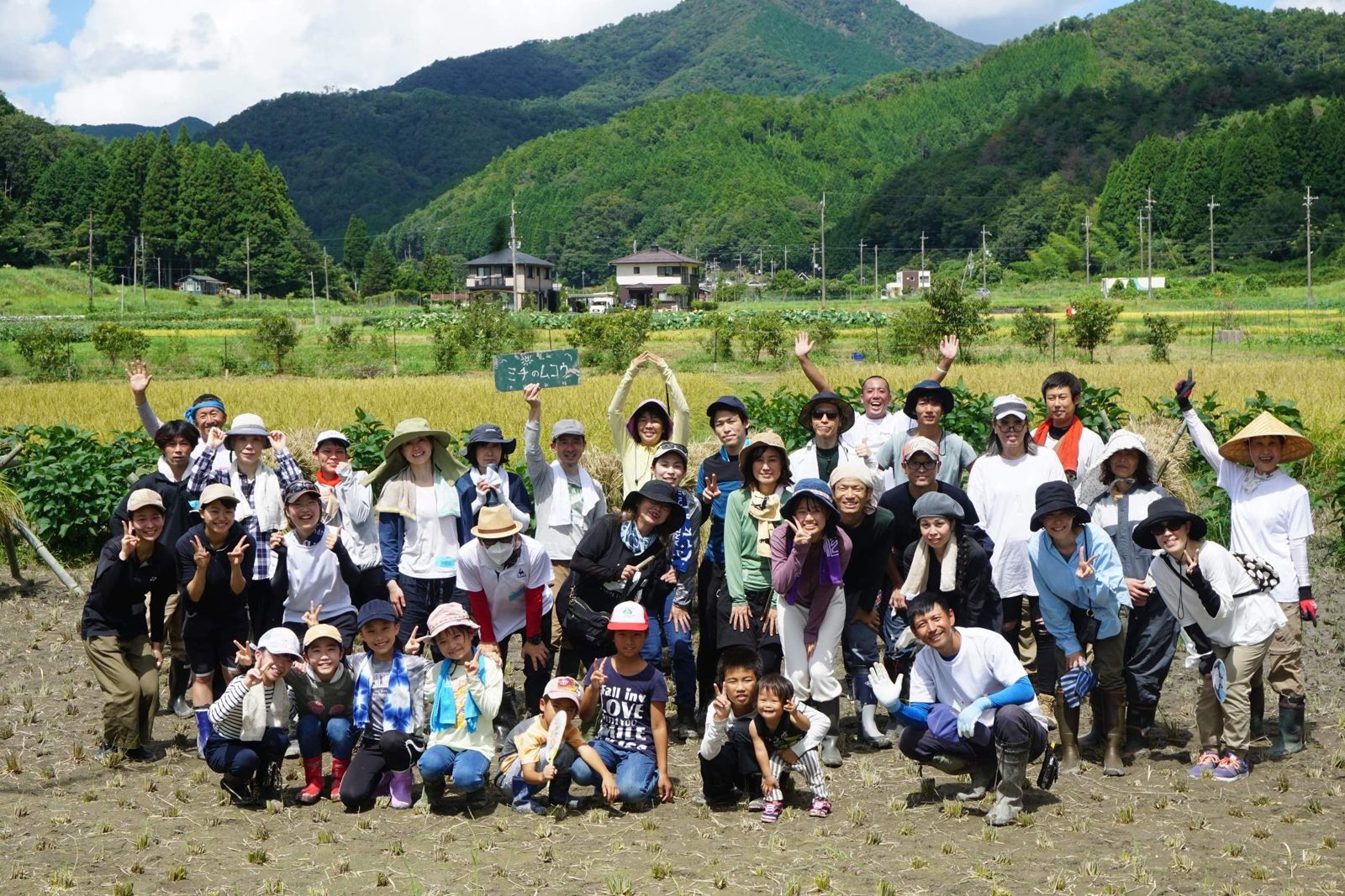 田んぼで、地域の皆さんと笑顔で並ぶ𠮷良佳晃
